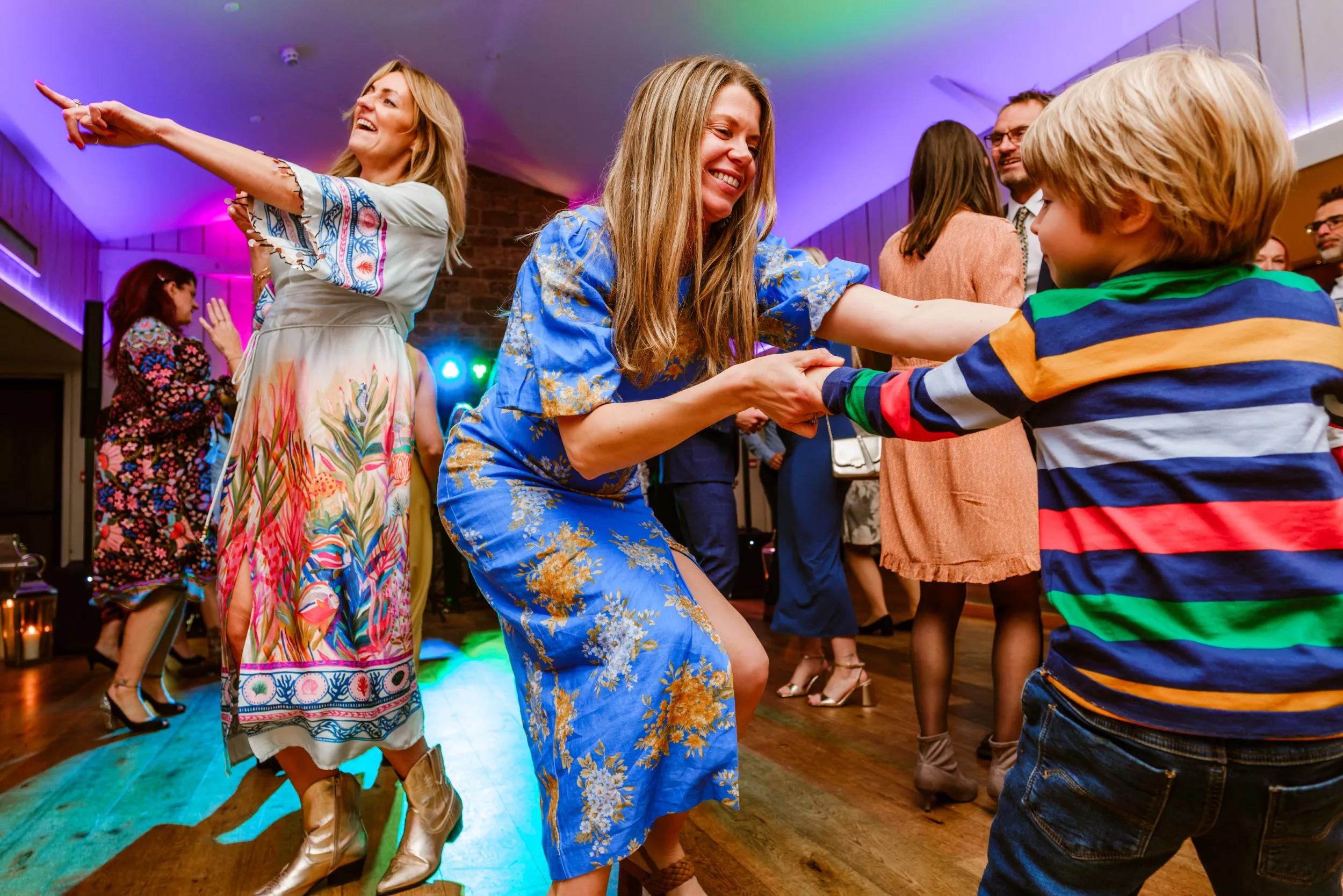 A very lively and colourful dancefloor scene at a wedding, with bold block colours and motion evoking a high energy moment.